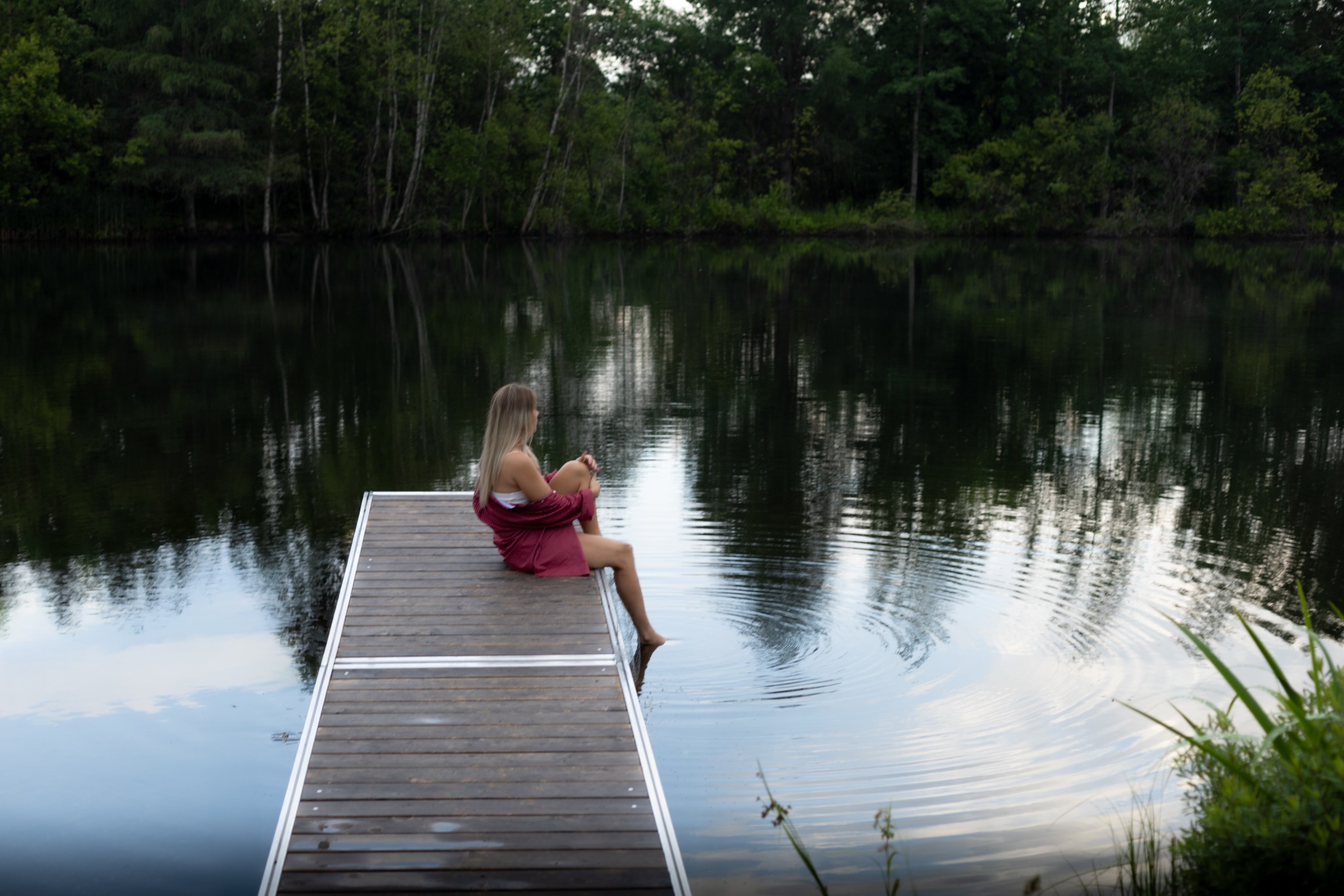A woman sitting quietly at the edge of a still lake